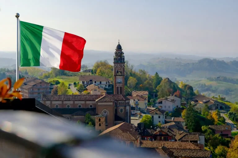 العمل التطوعي في إيطاليا داخل قرية إيطالية تقليدية مع العلم الإيطالي وخلفية طبيعية خلابة.