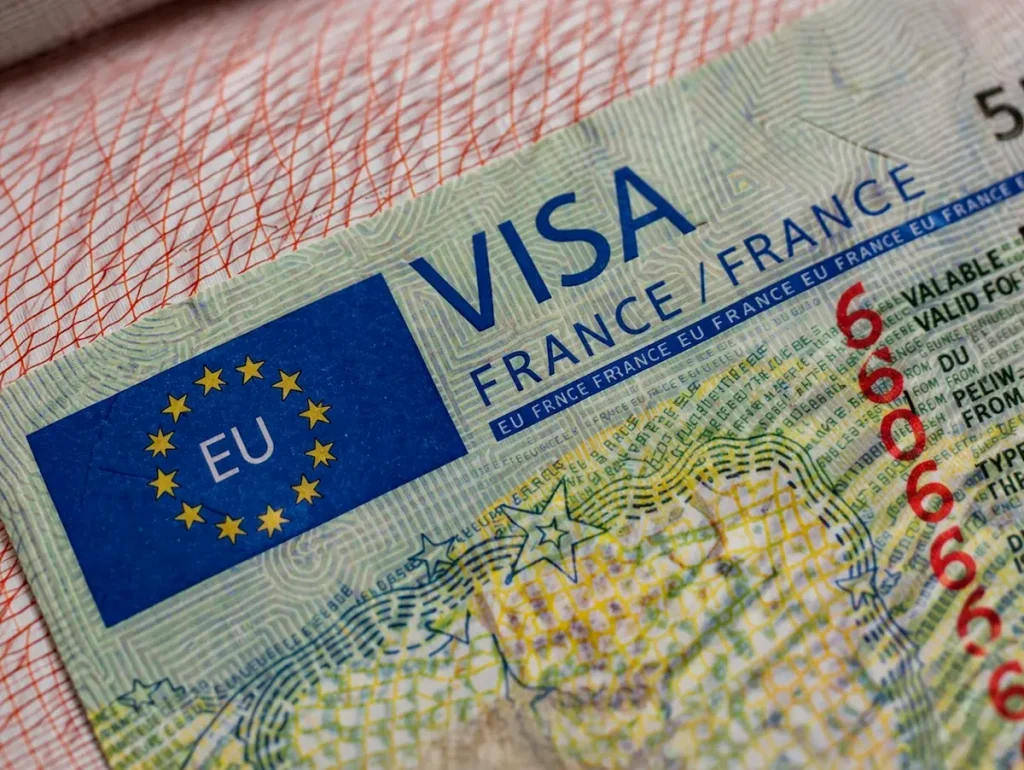 صورة مقربة واقعية لتأشيرة فيزا فرنسا على صفحة جواز سفر مع تفاصيل الأمان الدقيقة وعلم الاتحاد الأوروبي بشكل واضح.